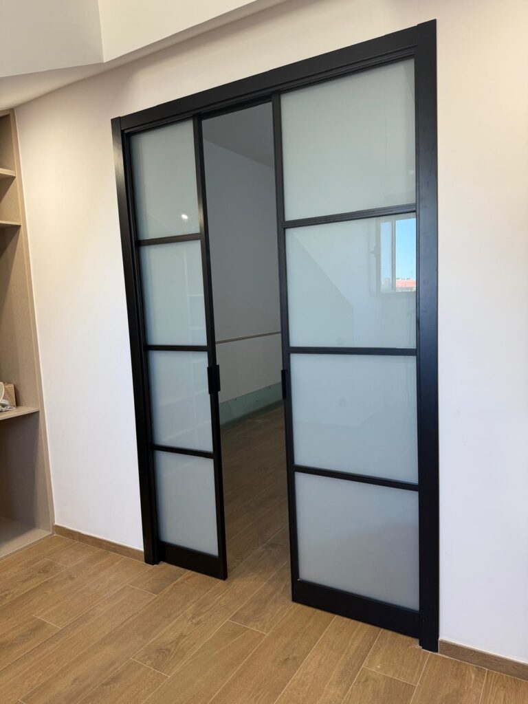 Puerta corredera de cristal con perfilería negra