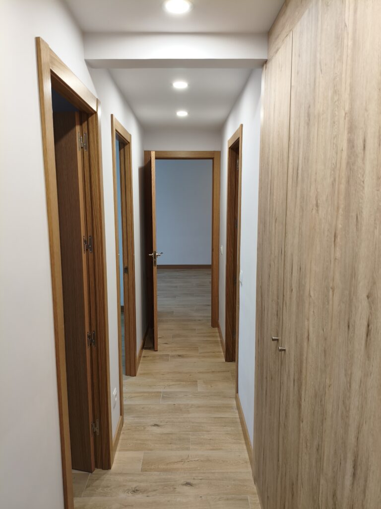 Pasillo con puertas y armario tras la reforma